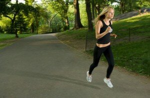 Красивая девушка блондинка в черной одежде бежит по парку