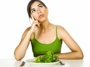 Женщина в зеленом платье с салатом в тарелке, ножом и вилкой